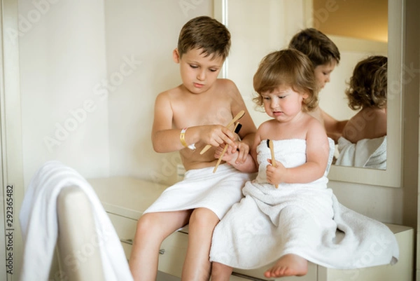 Fototapeta Cute toddler boy brushing his teeth after having a bath. Boy after evening before sleep rituals.