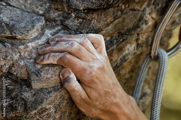 Fototapeta Closeup view of rock climber's hand gripping hold on natural cliff