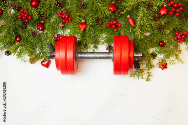 Obraz Christmas or New Year on a white background. Composition with dumbbells, gift, red glass balls, fir tree branches for healthy lifestyle and sport