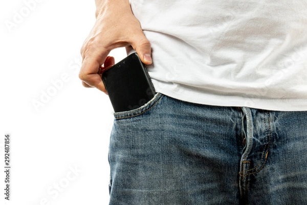 Obraz A man pulls a smartphone out of the front pocket of his jeans