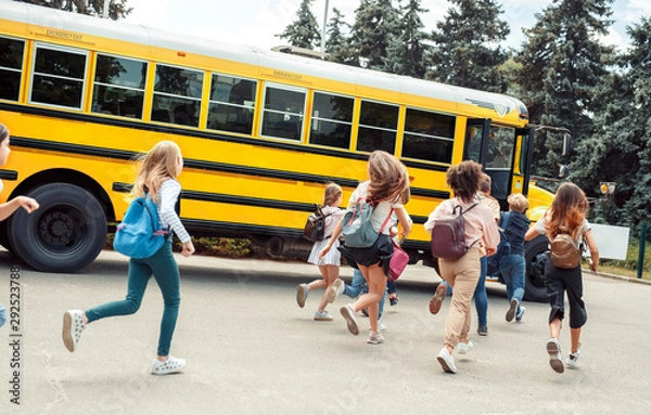 Fototapeta Classmates running to school bus back view late