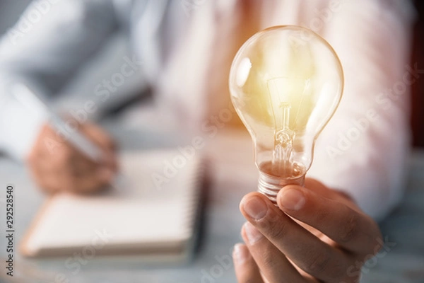Fototapeta man hand light bulb with notepad