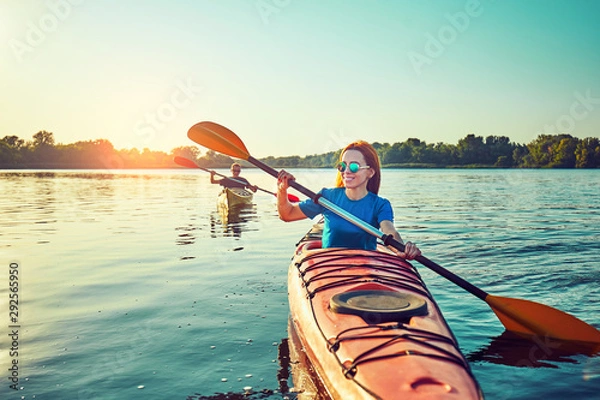 Fototapeta People kayak during sunset in the background. Have fun in your free time.