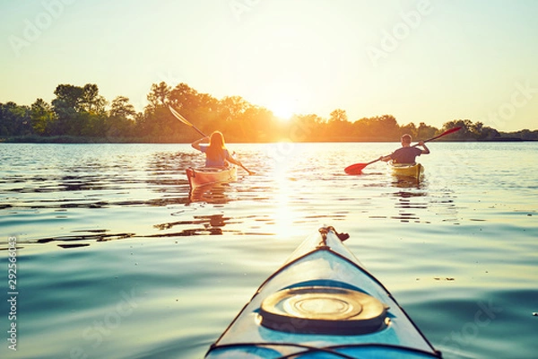 Fototapeta People kayak during sunset in the background. Have fun in your free time.