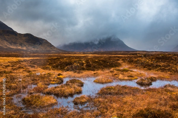 Fototapeta Buachaille Etive Mor shrouded in clouds with marshy water and grass in the foreground. Glencoe, Scotland