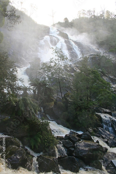 Fototapeta Standing at the bottom of a waterfall getting wet.