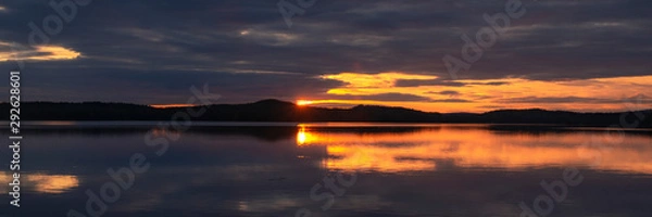 Fototapeta Water reflections at midnight sun at serene lake in finlandd