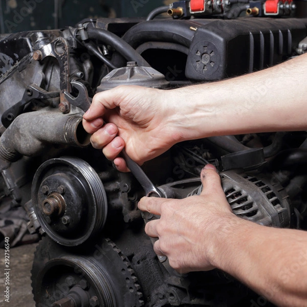 Fototapeta Car service - Engine repair mechanic hands with wrench generator nut