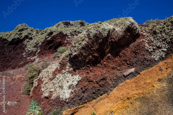 Fototapeta Red, orange and black stratified cliffs in Santorini Island