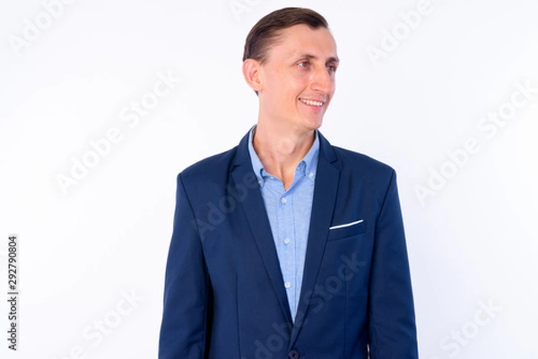 Fototapeta Studio shot of happy businessman in suit thinking and looking away