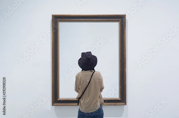 Obraz interior view of a lonely girl or tourist looking at blank canvas at a museum or gallery.