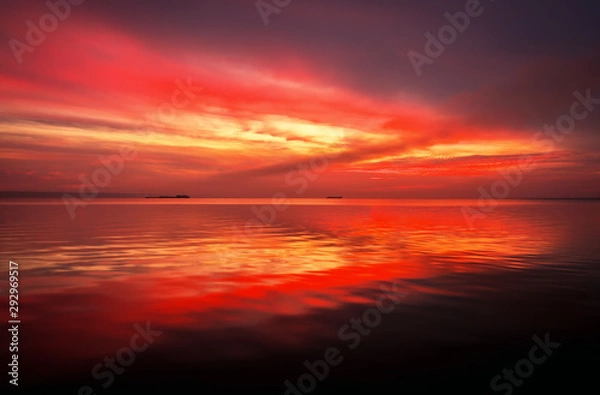Fototapeta Fiery dramatic landscape with the sea, beautiful sky and ships. Dawn. small waves, almost calm.