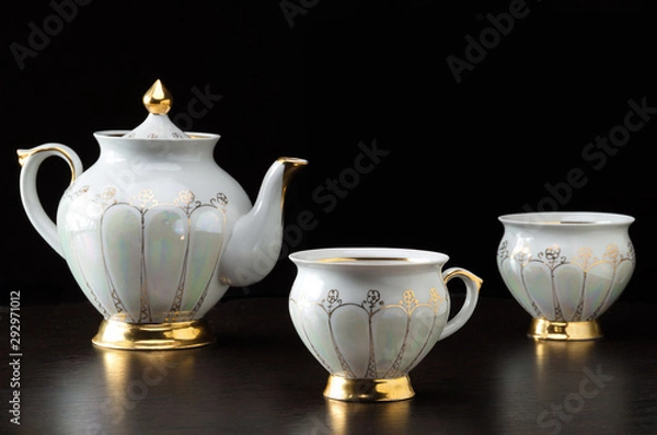 Obraz Elegant white tea cup an tea pot on dark background - selective focus