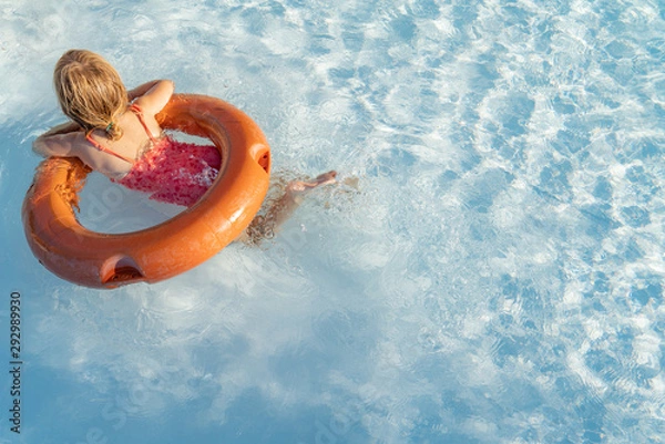 Obraz Young baby girl relaxing and swimming in the blue swimming pool with a orange circle closeup.