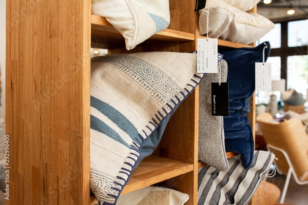 Fototapeta Assorted throw pillows in wooden shelf at store