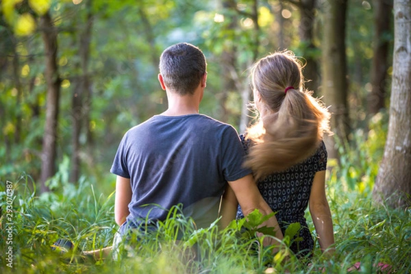Fototapeta Youg couple, man and a woman sitting together outdoors enjoying nature.