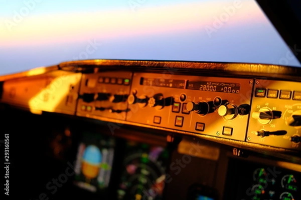 Obraz Airbus A320 flight deck and cockpit during flight. Overhead panel, flight control unit, PFD and ND visible. Integrity light and flood light. Lighting of the instruments at sunset and night.