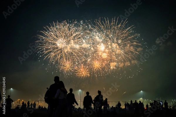 Obraz silhouettes of people watching fireworks in the background of bright flashes in the night sky