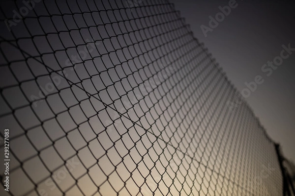 Fototapeta wire fence at sunset with unfocused background