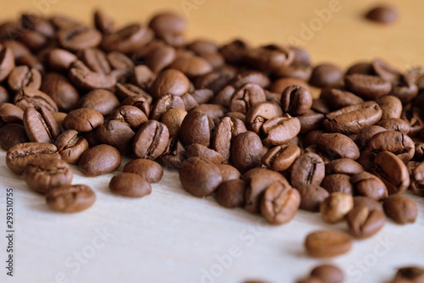 Fototapeta Roasted coffee beans scattered on a wooden surface close up