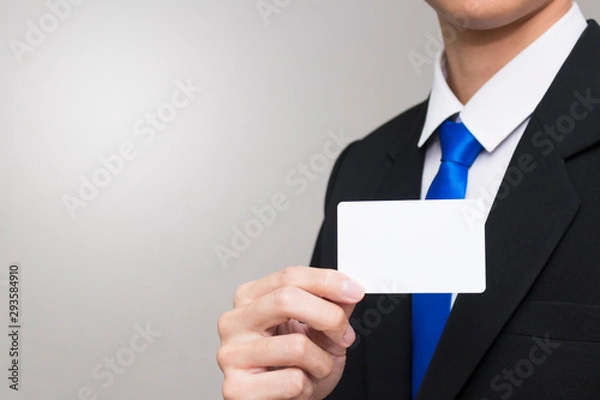 Fototapeta Business card in the hand of business people. Man wearing a black suit. There is copy space on the left.