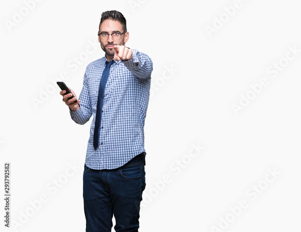 Fototapeta Young business man using smartphone over isolated background pointing with finger to the camera and to you, hand sign, positive and confident gesture from the front