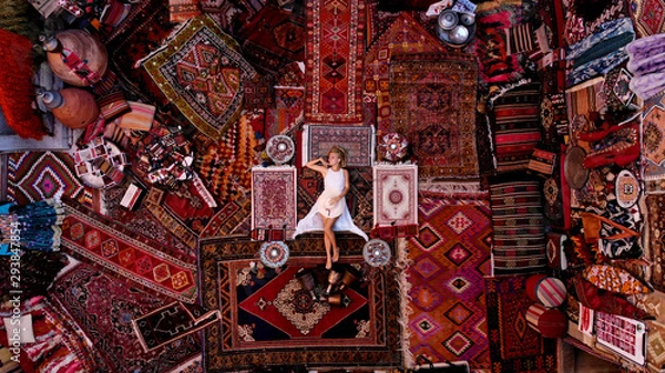 Obraz Piękna szczęśliwa dziewczyna w długiej białej sukni na dywan i dywaniki w Goreme, Kapadocja, Turcja. Dron z widokiem z góry.