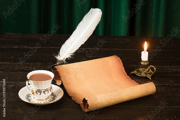 Fototapeta A cup of drink, a scroll of papyrus, a feather, and a candle in a candlestick against the background of green curtains
