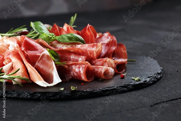 Fototapeta Marble cutting board with prosciutto, bacon, salami and sausages on wooden background. Rustic Meat platter
