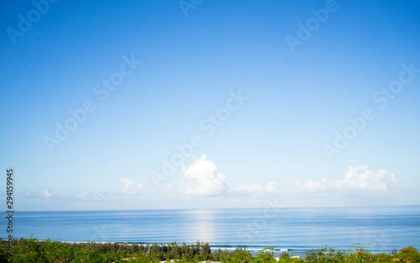 Fototapeta Tropical beach with clouds over the ocean and a beach with palm trees in summer. 