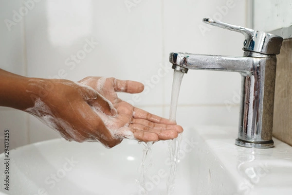 Fototapeta closeup of a boy scrubbing soapy hand against washbasin. Concept of a hand hygiene and global handwashing day