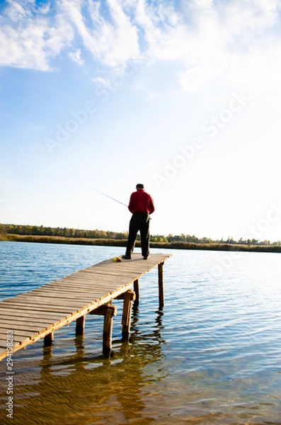 Fototapeta fisherman on a bridge near a blue lake