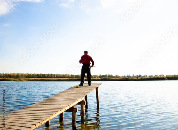 Fototapeta fisherman on a bridge near a blue lake