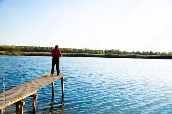 Fototapeta fisherman on a bridge near a blue lake