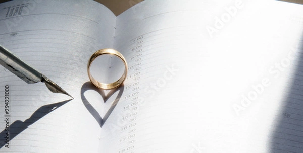 Obraz A golden ring in the middle of an open diary. Shadow in the shape of a heart. Nearby is a vintage fountain pen. Concept - Valentine's Day