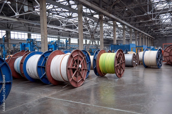 Obraz Several rows of large, heavy metal coils with electrical cables and wires in production. Modern line of automatic production of electric cable and wire. Coils on the concrete floor.