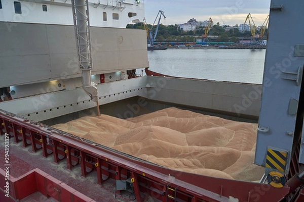 Obraz Grain loading in hold of bulk carrier ship with elevator crane closeup. Port grain elevator. Industrial sea trading port bulk cargo zone grain terminal