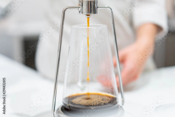Fototapeta process of preparation black coffee in chemex pour over coffee maker in bright modern cafe. Alternative ways of brewing coffee.