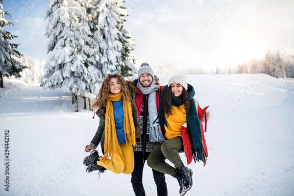 Obraz A group of cheerful young friends standing outdoors in snow in winter forest.