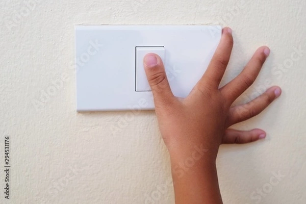 Obraz Close up thumb finger’s kid is turning on or turning off the light-switch.
