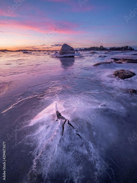 Fototapeta A single rock breaks through the sheet of ice over the sea in the Swedish archipelago.