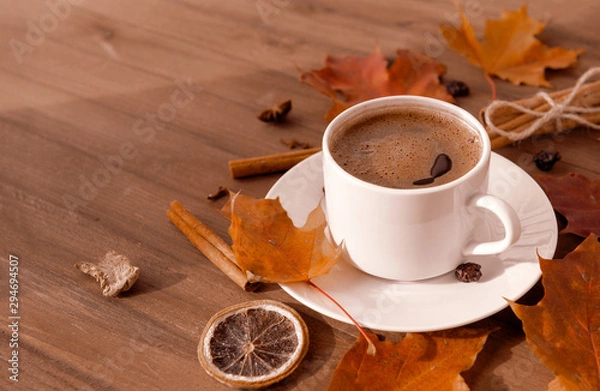 Fototapeta Cup of coffee with black coffee in a saucer on a wooden background, red fallen autumn leaves, cinnamon, a slice of dried orange