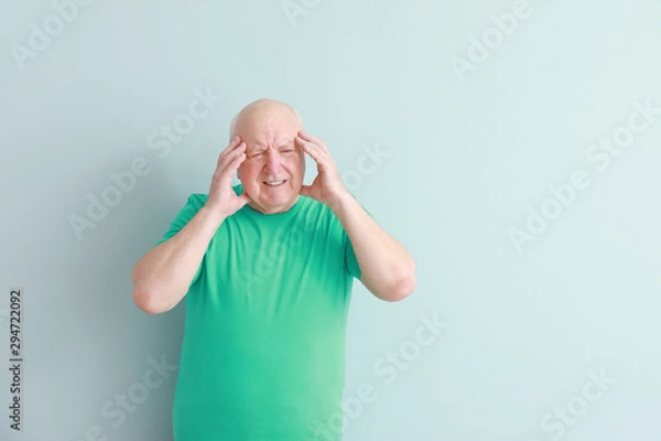 Fototapeta Senior man suffering from headache on light background