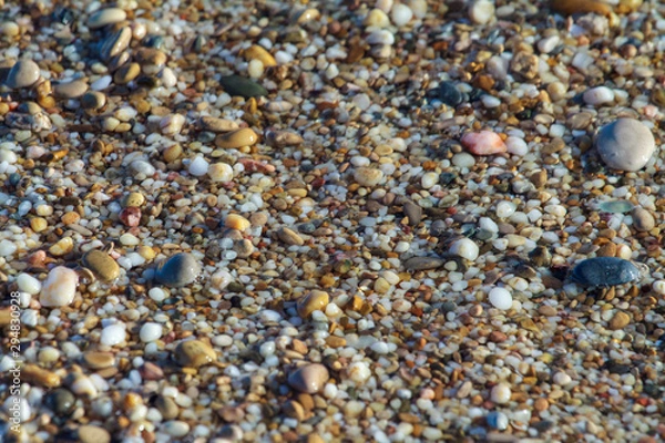 Fototapeta sea pebbles colored granite on the beach background stones. The shore of the beach with sand and pebbles washed by the waves of the sea.