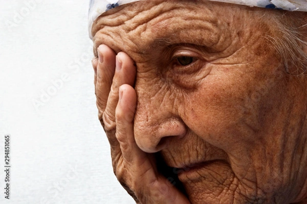 Fototapeta Old saddened mother, portrait photo. The old woman closes her eyes filled with tears, close-up