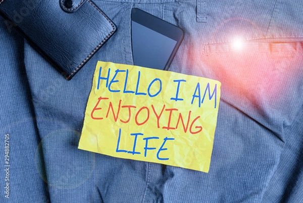 Fototapeta Writing note showing Hello I Am Enjoying Life. Business concept for Happy relaxed lifestyle Enjoy simple things Smartphone device inside trousers front pocket with wallet