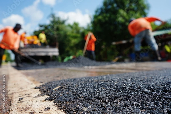 Fototapeta Repairing a damaged road By adjusting the level with asphalt mixed with small stones (picture blurred)