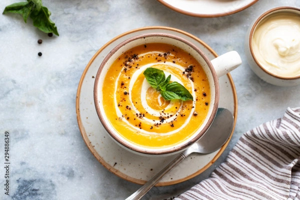 Obraz Yellow carrot or pumpkin soup with bread and sour cream on white marble background. Copy space. Homemade carrot soup puree and flatbread. Healthy eating. Halloween, thanksgiving. Top view. Flat lay.