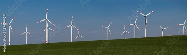 Obraz Panorama dużej farmy wiatrowej na lądzie na zielonej łące przed błękitnym niebem