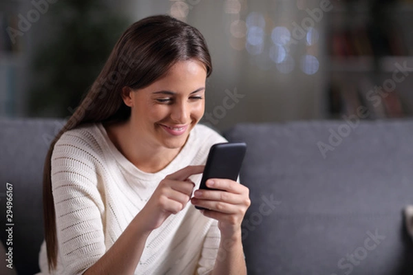 Fototapeta Happy teen browsing mobile phone content in the night